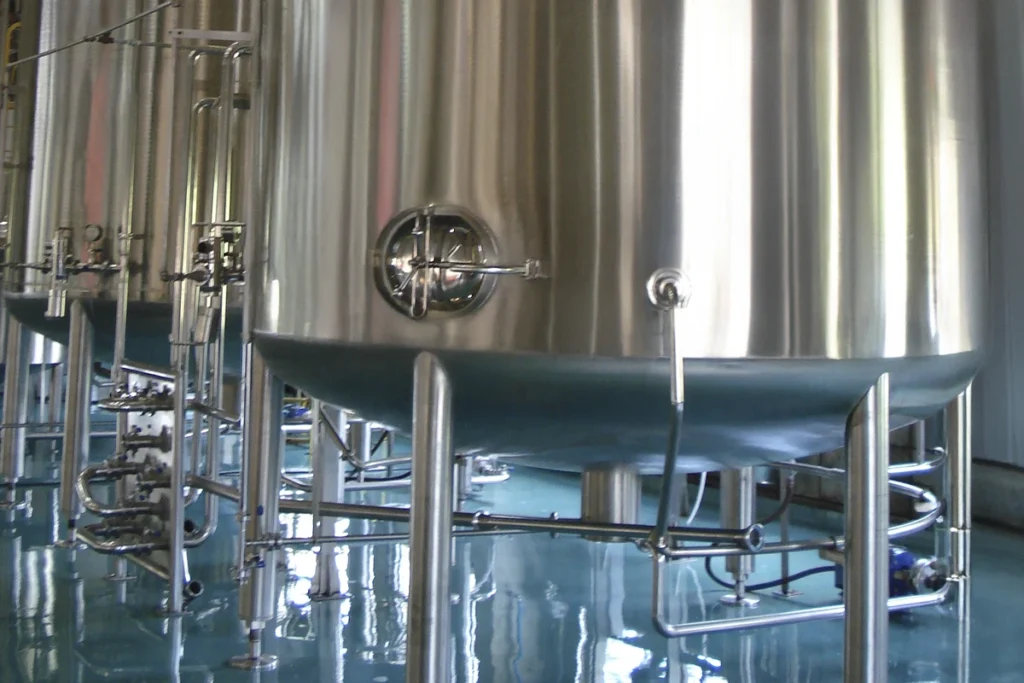 Detalhe de tanque de aço inoxidável com acabamento sanitário, representando excelência em armazenamento para a indústria de bebidas.