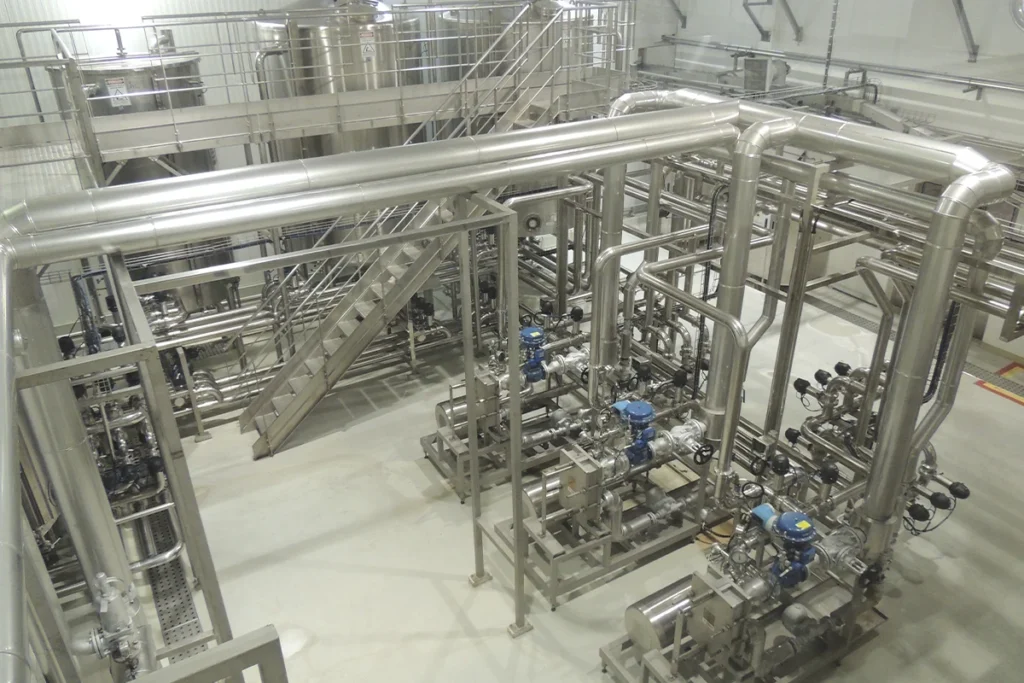 Estrutura industrial em aço inoxidável, destacando sistemas integrados para produção eficiente de bebidas.