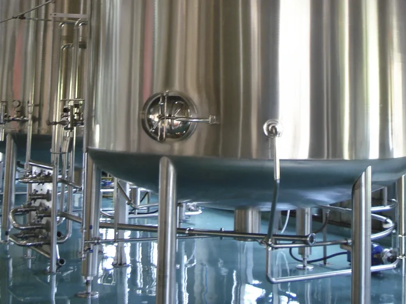 Detalhe de tanque de aço inoxidável com acabamento sanitário, representando excelência em armazenamento para a indústria de bebidas.