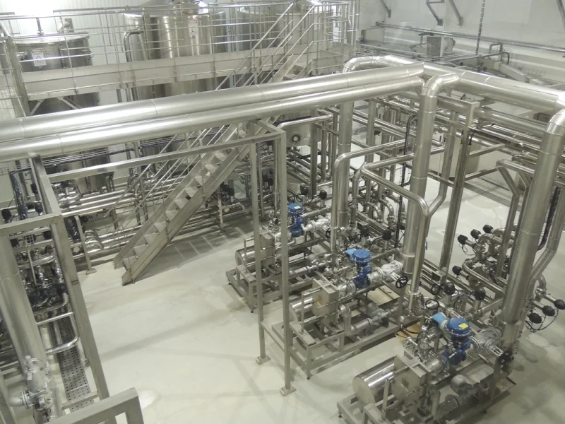 Estrutura industrial em aço inoxidável, destacando sistemas integrados para produção eficiente de bebidas.