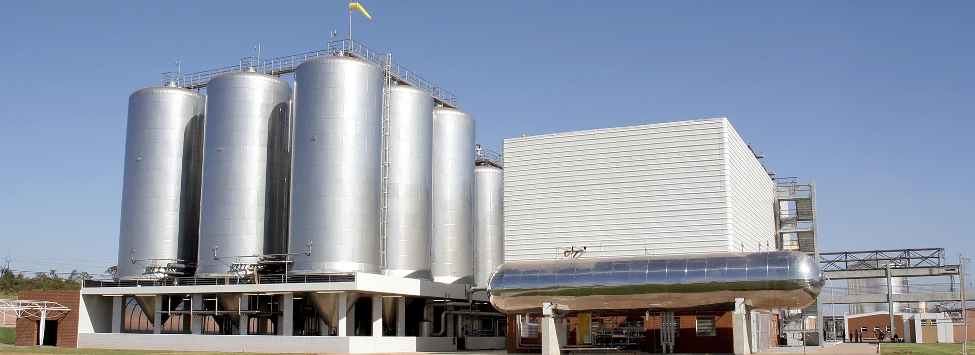 Unidade industrial com tanques externos de grande capacidade, evidenciando robustez e soluções escaláveis para o setor de bebidas.